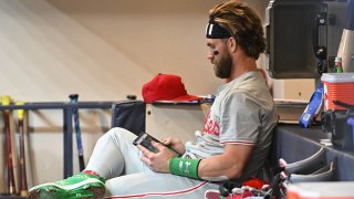 Sep 16, 2024; Milwaukee, Wisconsin, USA; Philadelphia Phillies first base Bryce Harper (3) looking over some images in the dugout in the top of the eighth inning against the Milwaukee Brewers at American Family Field. Mandatory Credit: Michael McLoone-Imagn Images